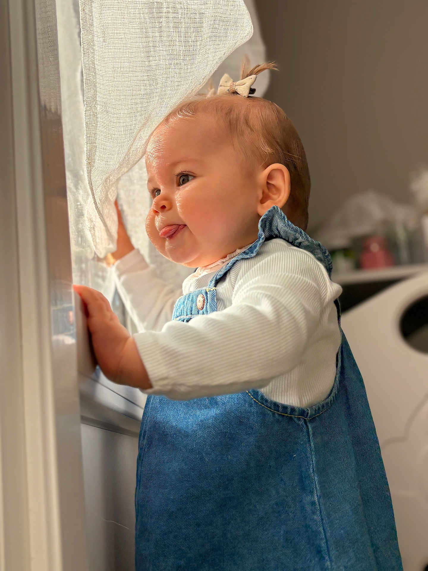 Haïvie a rejoint le concours — aidez-le/la à gagner de superbes lots ! baby, infant, child, denim_dress, window, curtain, sunlight, tongue_out, profile, ear, hand, eyes, cheeks, hair_bow, indoor, portrait, soft_focus, cute, clothing, nursery