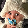 adorable, animal_design, baby, child, close_up, clothing, cozy, cute, expression, eyes, face, fluffy, hand, hat, indoor, infant, pacifier, portrait, soft, warm