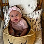 baby, basket, chair, child, clothing, comfort, cushion, cute, expression, fabric, face, headband, indoor, infant, pillow, pink, smile, stuffed_toy, wood, woven