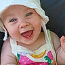 baby, child, smiling, hat, white_hat, colorful_clothing, fruit_pattern, toy, outdoor, sunlight, happy, laughing, blue_eyes, cute, infant, person, summer, playful, sitting, closeup