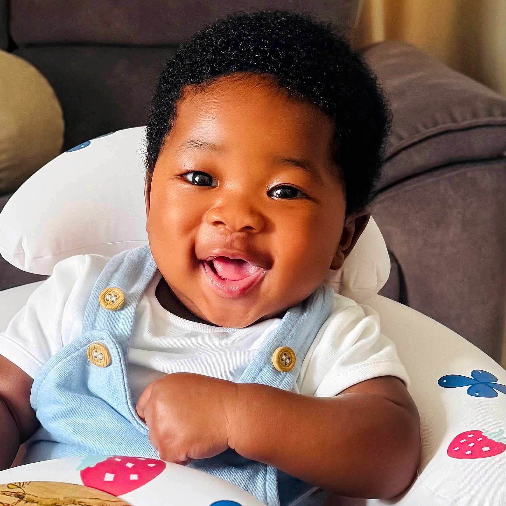 Kenechukwu is registered to the contest to win money with this photo: african_american, baby, baby_clothing, baby_seat, button, child, closeup, couch, cute, face, furniture, happy, indoor, infant, one_person, overalls, portrait, smiling, white_shirt, young_child