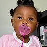Loyal is registered to the contest to win money with this photo: toddler, child, baby, portrait, pacifier, pink_clothing, hair_buns, sitting, indoors, person, face, eyes, fashion, infant, adult_hand, phone_screenshot, date, time, furniture, candid
