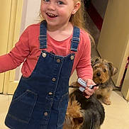 Zoe a rejoint le concours — aidez-le/la à gagner de superbes lots ! child, girl, smiling, indoor, denim_dress, pink_tights, black_boots, toy, hairbrush, dog, two_dogs, floor, doorway, happy, person, pet, animal, home, curly_hair, playful