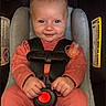 Indy joined the competition — help win amazing prizes! baby, child, car_seat, evenflo, orange_clothing, pacifier, harness, infant, smiling, cute, hands, sitting, safety, seatbelt, indoor, portrait, face, person, young, happy