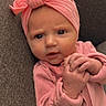 Indy is registered to the contest to win money with this photo: baby, infant, pink_clothing, headband, hands, face, expression, couch, fabric, closeup, child, person, indoor, cute, skin, portrait, newborn, apparel, headwear, seated