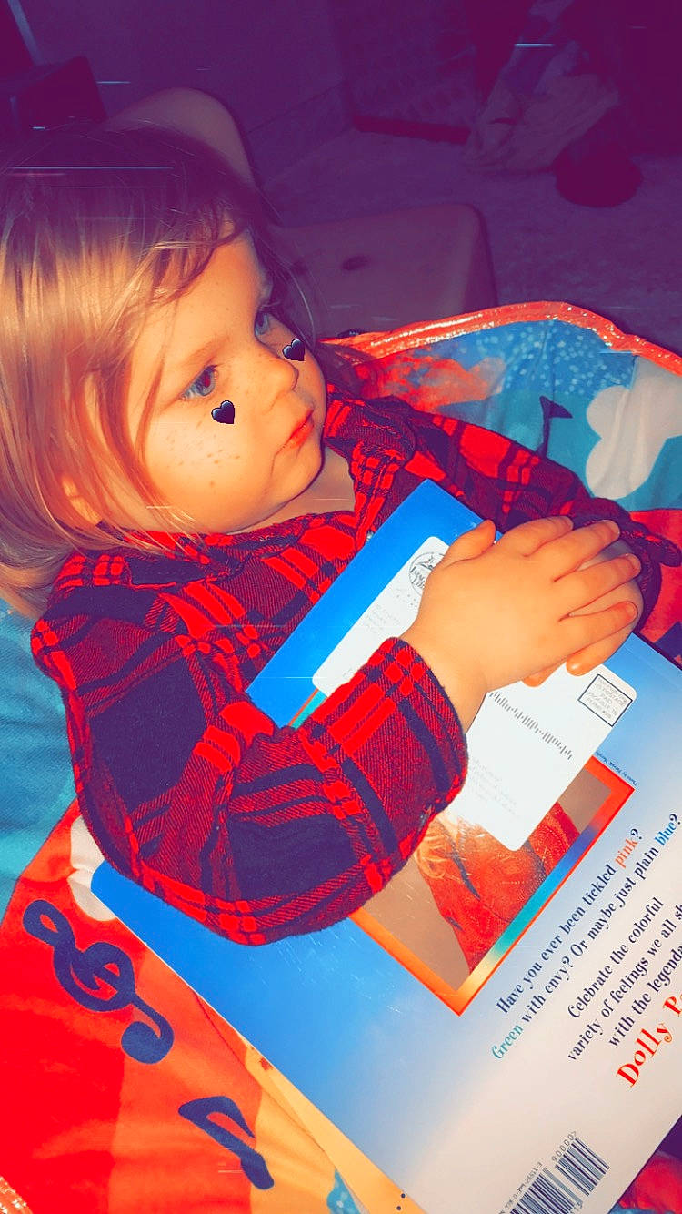 Luka is registered to the contest to win money with this photo: arm, baby, book, carmine, chair, child, electric_blue, finger, hand, happy, homework, human_body, illustration, office_supplies, person, play, room, sitting, toddler, writing