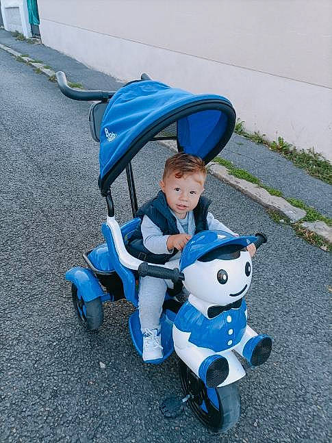 Kaan participe au concours pour gagner de l'argent avec cette photo : asphalt, automotive_design, azure, baby, baby_carriage, baby_products, baby_toddler_clothing, blue, electric_blue, fun, person, plant, product, public_space, recreation, riding_toy, rolling, sitting, tire, toddler