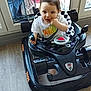 child, toddler, toy_car, indoor, window, clothing, nike, floor, curious, baby, seat, hand, face, person, play, black, white, plastic, smile, furniture