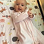 baby, infant, onesie, pink_clothing, lying_down, animal_pattern, blanket, cute, child, face, hands, playful, indoor, portrait, young_child, smiling, soft_lighting, bed, sleepwear, cozy