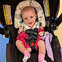 baby, infant, car_seat, pink_outfit, smiling, blue_eyes, blanket, socks, straps, cushion, indoor, child, happy, seated, head_support, fabric, safety, cute, portrait, person