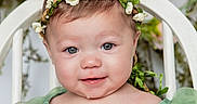 Willow is registered to the contest to win money with this photo: baby, child, smile, green_dress, flower_crown, chair, pink_flowers, portrait, cute, infant, headband, tulle, blush, happy, person, closeup, indoors, soft_lighting, decor, young