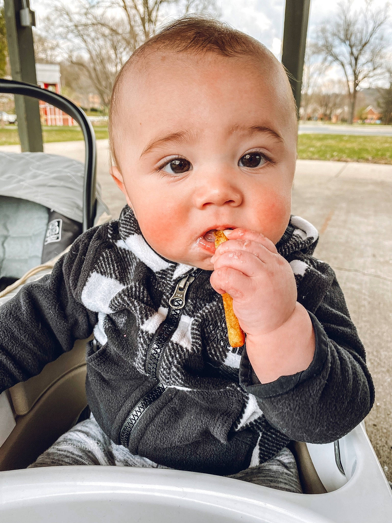 Oakland is registered to the contest to win money with this photo: baby, cheek, child, eating, eye, face, finger, food, head, nose, person, side_dish, sitting, skin, toddler, vacation