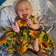 Amayah joined the competition — help win amazing prizes! baby, child, smiling, laughing, dress, sunflower_pattern, blanket, seat, indoors, footwear_absent, happy, infant, person, clothing, cute, sitting, head, face, joy, comfort