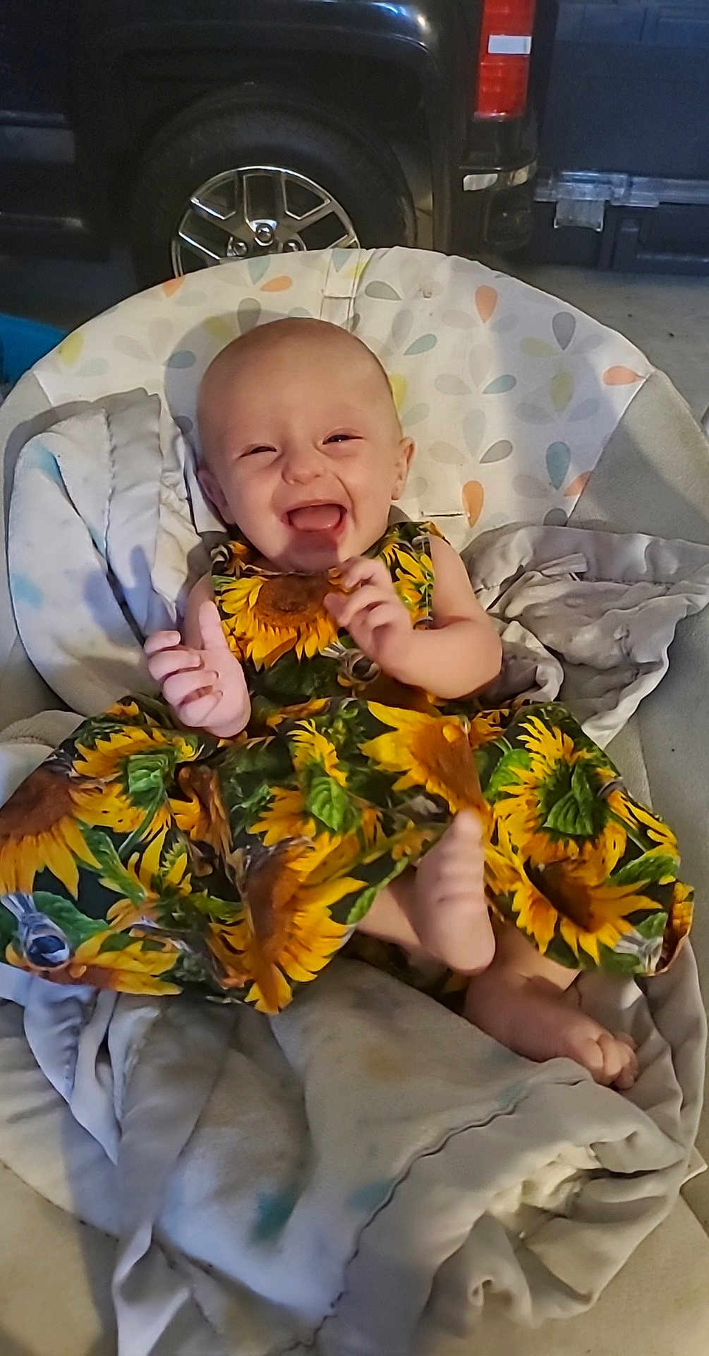 Amayah joined the competition — help win amazing prizes! baby, child, smiling, laughing, dress, sunflower_pattern, blanket, seat, indoors, footwear_absent, happy, infant, person, clothing, cute, sitting, head, face, joy, comfort