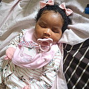 Truett is registered to the contest to win money with this photo: baby, sleeping, pacifier, pink_bow, mittens, blanket, pajamas, cute, infant, child, indoor, soft_lighting, closeup, person, resting, cozy, head, face, adorable, home