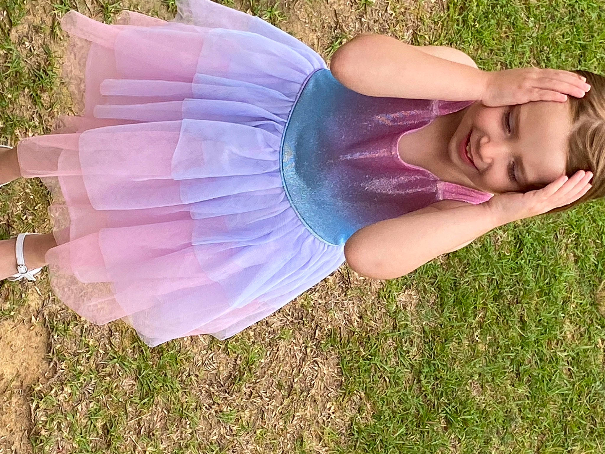 Piper is registered to the contest to win money with this photo: abdomen, child, electric_blue, fashion_accessory, fun, grass, grass_family, grassland, happy, human_leg, joy, lawn, leisure, magenta, people_in_nature, person, plant, sitting, smile, thigh