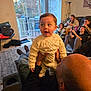 Jeremiah is registered to the contest to win money with this photo: toddler, child, adult, living_room, people, sweater, knitwear, bald_head, couch, carpet, glass_door, window, indoor, group, seated, relaxing, casual_clothing, smiling, family, home