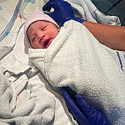 Kianna-Rae is registered to the contest to win money with this photo: newborn, baby, hospital, towel, wrapped, gloved_hands, medical, infant, hat, person, bed, blanket, healthcare, cute, face, skin, lying_down, care, patient, fresh
