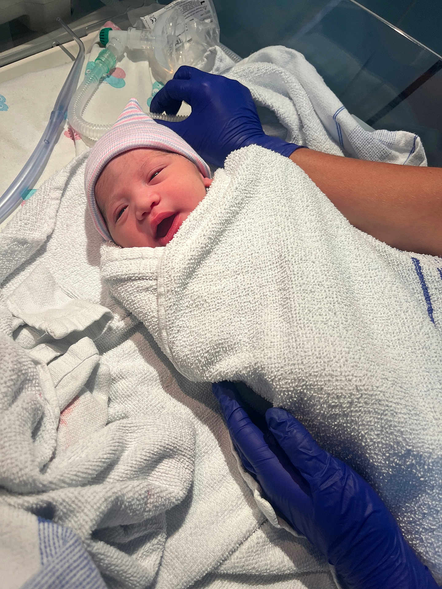 Kianna-Rae is registered to the contest to win money with this photo: newborn, baby, hospital, towel, wrapped, gloved_hands, medical, infant, hat, person, bed, blanket, healthcare, cute, face, skin, lying_down, care, patient, fresh