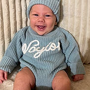 Waylon joined the competition — help win amazing prizes! baby, infant, smiling, knitwear, hat, blue_clothing, sitting, cozy, happy, cute, portrait, indoor, child, soft_texture, blanket, fuzzy_background, warm_clothing, face, young_child, candid