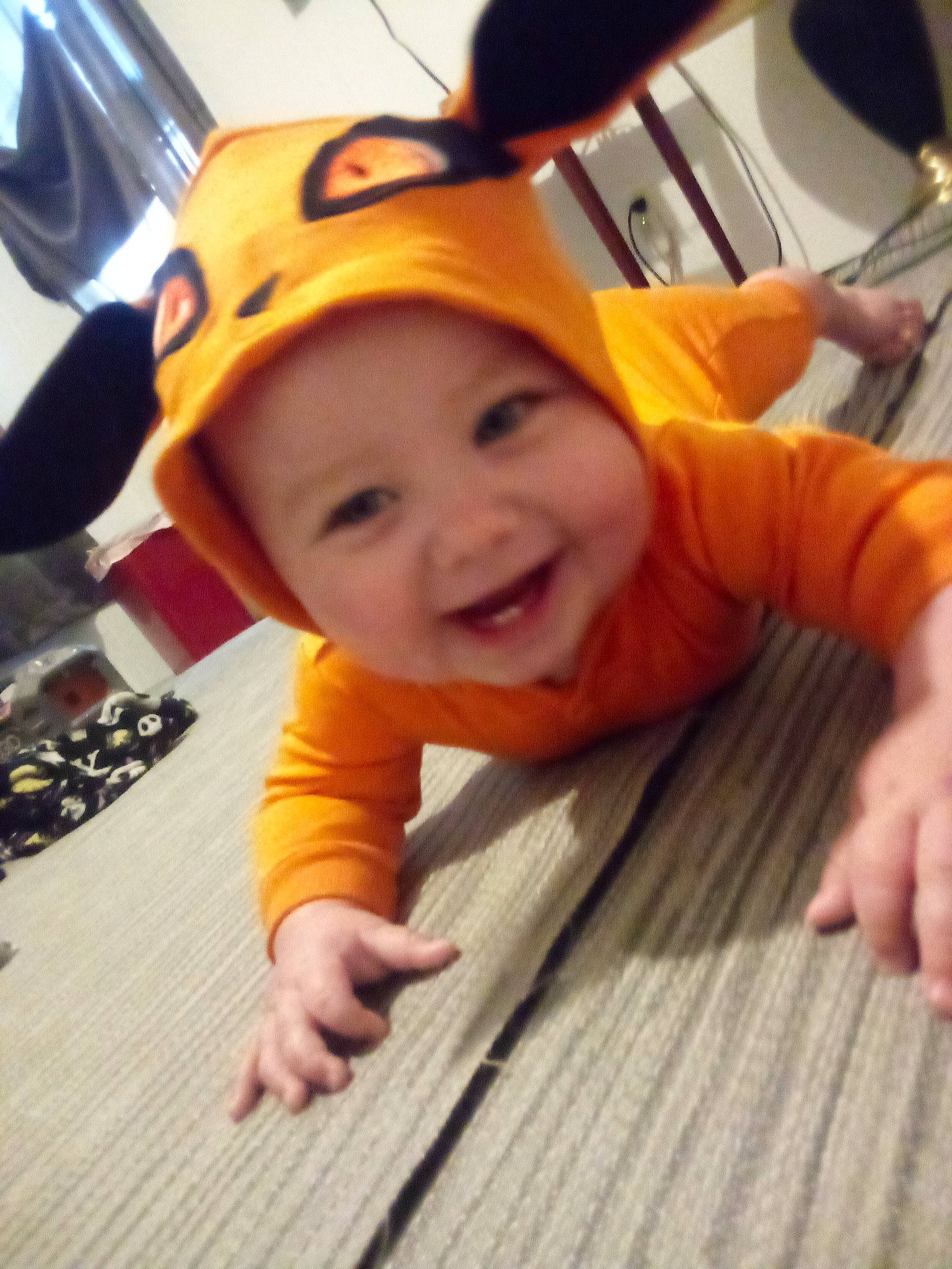 Emory is registered to the contest to win money with this photo: baby, baseball_cap, cap, child, fashion_accessory, flooring, fun, gesture, happy, headwear, joy, laugh, orange, person, personal_protective_equipment, play, recreation, selfie, sitting, smile