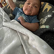 Idan joined the competition — help win amazing prizes! baby, infant, blanket, pillow, onesie, face, hand, eyes, mouth, zebra_pattern, giraffe_pattern, boppy_pillow, bedding, soft_texture, cozy, portrait, indoor, couch, arm, sleepy