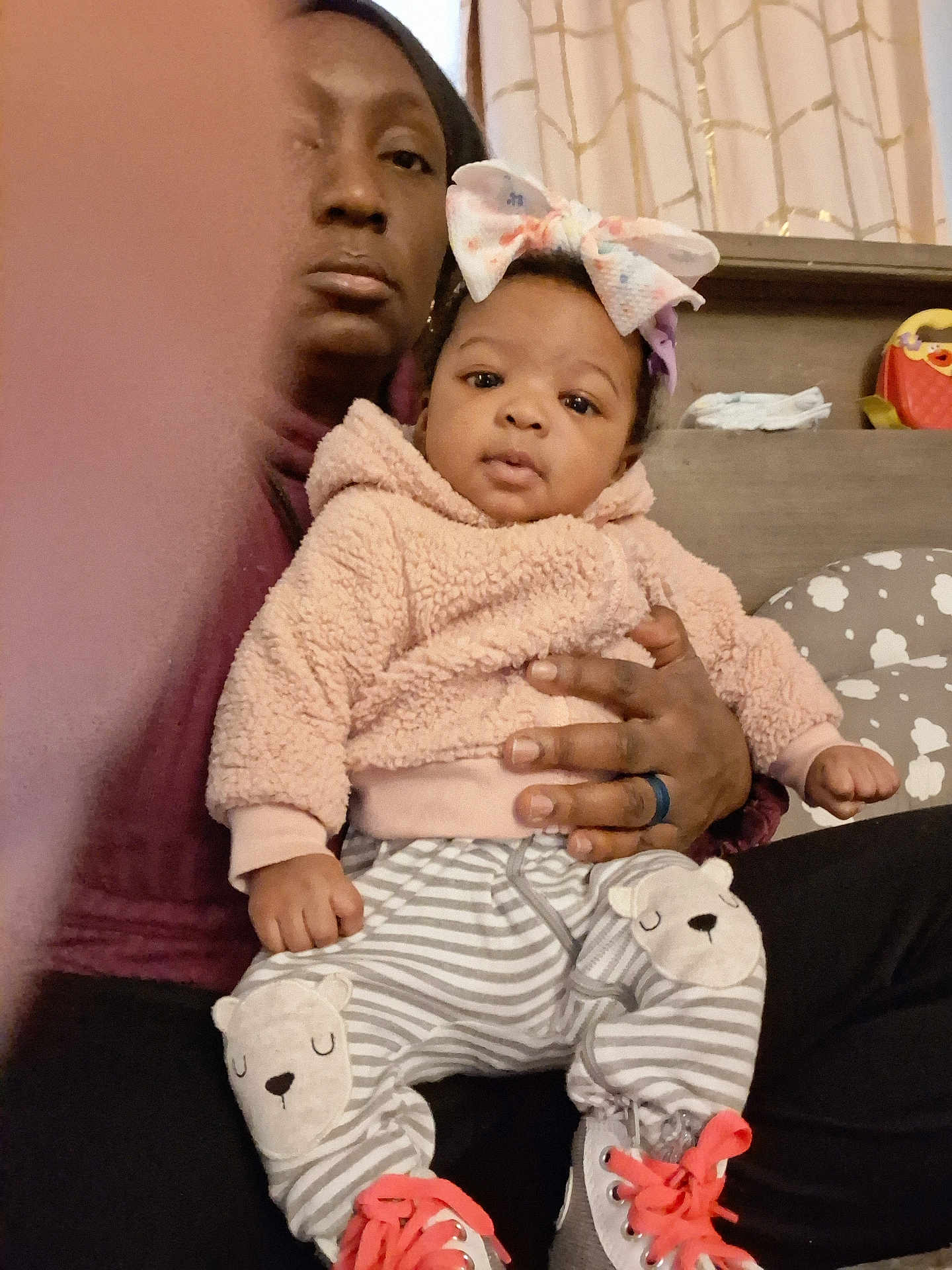 Miracle is registered to the contest to win money with this photo: baby, child, adult, person, indoor, clothing, hoodie, pants, bow, headband, hand, shoe, sneaker, striped, pattern, furniture, curtain, candid, portrait, casual