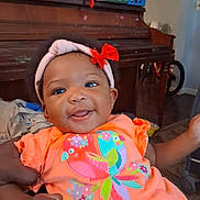 Miracle joined the competition — help win amazing prizes! baby, child, smiling, headband, bow, orange_dress, colorful, indoors, piano, furniture, person, happy, cute, infant, portrait, hand, room, decor, clothing, holding