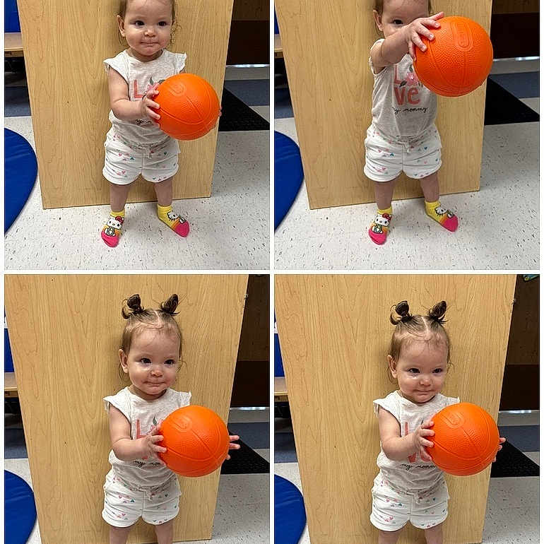 Allyana is registered to the contest to win money with this photo: toddler, child, orange_ball, colorful_socks, double_buns, indoor, wooden_panel, playful, smiling, standing, floor_tiles, white_clothing, shorts, shirt, cute, young_child, person, play, ball, happy