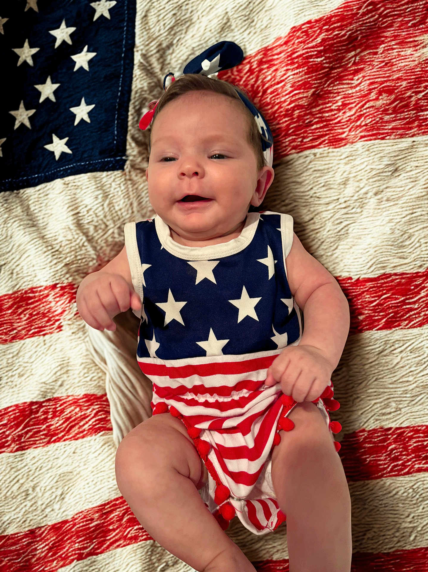 Allyana joined the competition — help win amazing prizes! american_flag, baby, celebration, child, clothing, cute, fabric, happy, headband, infant, lying_down, patriotic, pattern, person, portrait, red_white_blue, smiling, stars, stripes, texture