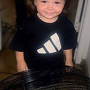 Leonardo is registered to the contest to win money with this photo: toddler, child, smiling, black_shirt, fan, hair_blown, indoor, floor, logo, playful, happy, person, young_child, cute, funny_hair, electric_fan, short_sleeves, standing, home, portrait