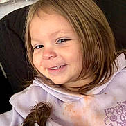 Leonardo is registered to the contest to win money with this photo: child, girl, smiling, portrait, indoors, light_brown_hair, ponytail, sweatshirt, purple_clothing, face, happy, casual, cozy, home, person, seated, young_child, cute, clothing, expression