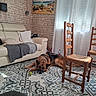 dog, german_shepherd, living_room, sofa, chair, blanket, pillow, curtains, tile_floor, painting, window, sunlight, tennis_ball, wooden_chair, relaxed, interior, home, decor, comfort, pet