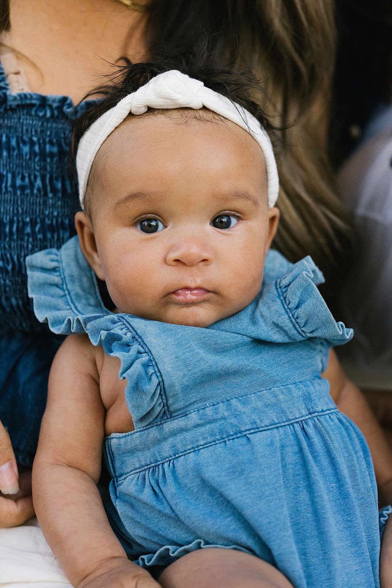Emanii joined the competition — help win amazing prizes! baby, infant, child, headband, blue_dress, denim_dress, ruffled_sleeves, big_eyes, closeup, portrait, lap, hand, parent, skin, hair, gaze, cute, soft_light, warm_tone, sitting