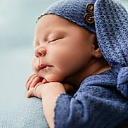 Jaxton is registered to the contest to win money with this photo: newborn, baby, sleeping, blue_hat, knitwear, soft_texture, peaceful, portrait, closeup, infant, resting, cute, child, face, hands, cozy, button, warm, calm, soft_light