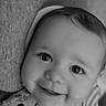 baby, smiling, face, close_up, portrait, infant, child, cute, eyes, cheeks, onesie, patterned_clothing, soft_texture, monochrome, black_and_white, happy, lying_down, headwear, young_child, adorable