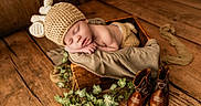Jaxton is registered to the contest to win money with this photo: baby, sleeping, knitted_hat, wooden_box, brown_boots, greenery, wooden_floor, cozy, infant, cute, resting, soft_fabric, hat_with_ears, newborn, portrait, indoor, peaceful, warm_lighting, decor, child