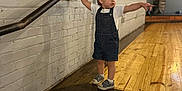 Jeffery is registered to the contest to win money with this photo: toddler, child, denim_overalls, white_tshirt, pointing, standing, wooden_steps, handrail, brick_wall, indoor, floor, curious, casual_clothing, footwear, short_hair, person, young_child, expression, gesture, lighting