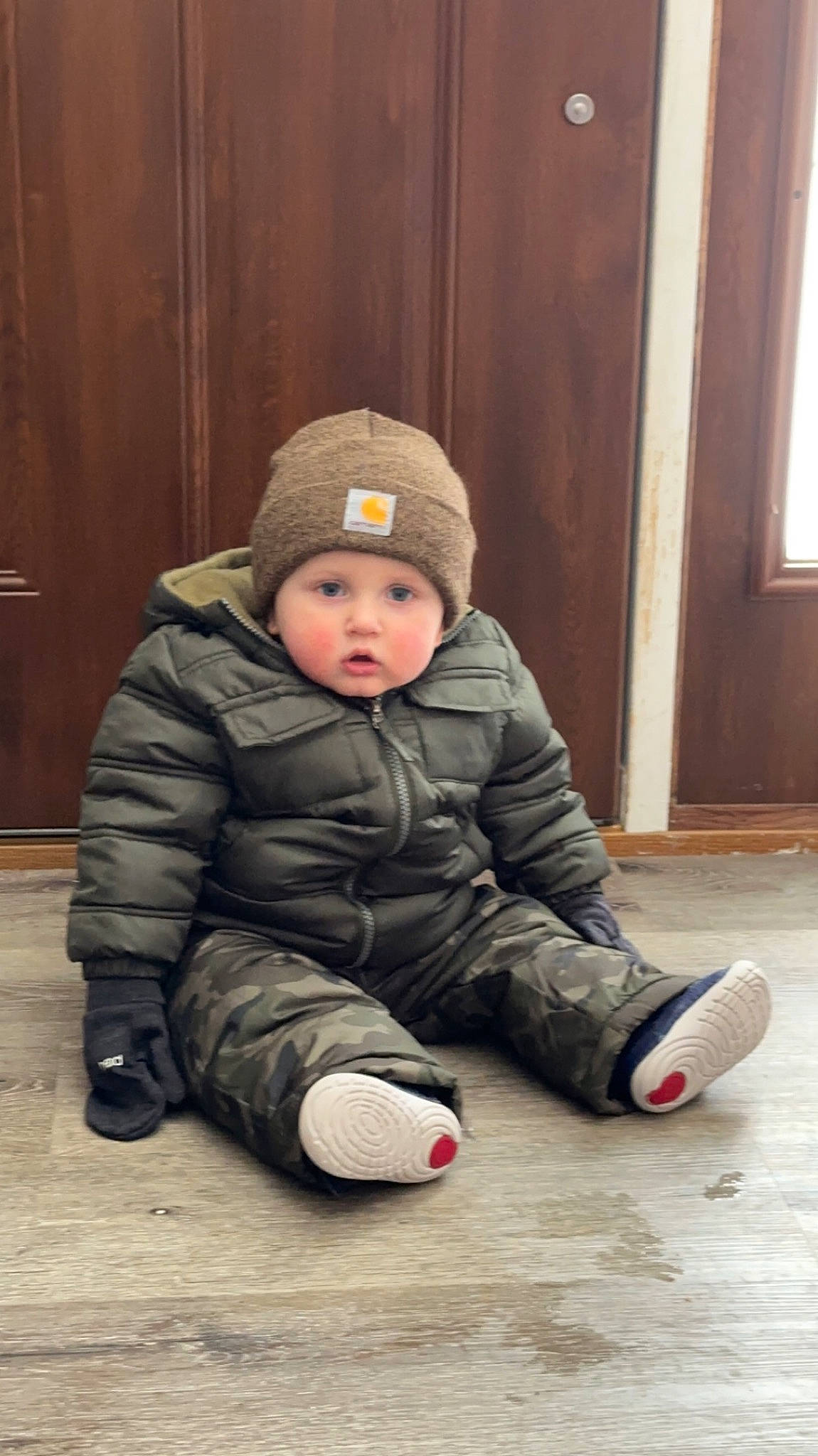 Kooper is registered to the contest to win money with this photo: baby, baby_toddler_clothing, cap, cheek, child, comfort, face, floor, flooring, hardwood, headwear, human, leg, people, person, sitting, standing, toddler, tree, window