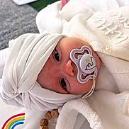 Remmie joined the competition — help win amazing prizes! baby, infant, pacifier, white_clothing, head_wrap, blanket, rainbow, cloud, soft_texture, closeup, face, cute, lying_down, child, newborn, indoors, comfort, warm, sleepwear, baby_accessory