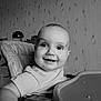 baby, child, high_chair, smiling, happy, face, hand, indoor, furniture, table, clothing, person, portrait, monochrome, black_and_white, wallpaper, lamp, room, cute, toddler