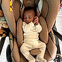 baby, sleeping, car_seat, pajamas, infant, child, stroller, floor, toy, footwear, brown, cream, comfort, indoor, head_support, rest, peaceful, padding, clothing, person