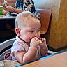 baby, child, high_chair, restaurant, snack, eating, sitting, face, portrait, indoors, adult, man, baseball_cap, camouflage_shirt, booth, table, food, happy, family, candid