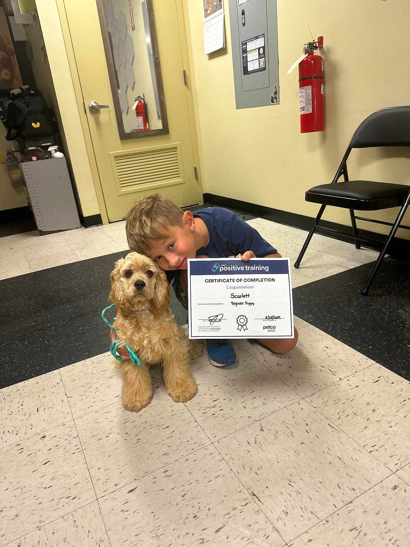 Scarlett joined the competition — help win amazing prizes! boy, puppy, certificate, indoor, floor, dog, child, smiling, leash, chair, fire_extinguisher, door, wall, tile_floor, clothing, hair, person, training, achievement, petco