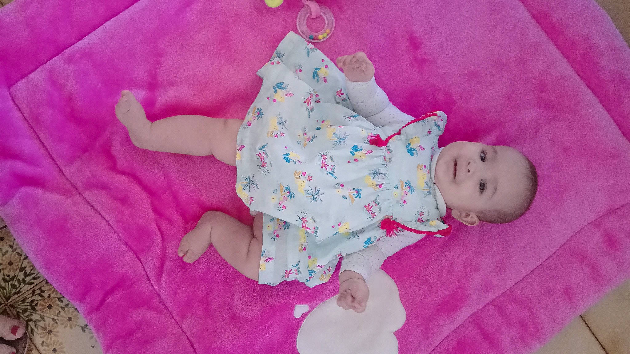 Lise participe au concours pour gagner de l'argent avec cette photo : arm, baby, baby_toddler_clothing, child, comfort, dress, finger, happy, human_body, leg, linens, magenta, pattern, person, pink, purple, skin, sleeve, textile, toddler