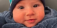 Elias a rejoint le concours — aidez-le/la à gagner de superbes lots ! baby, child, face, smile, hat, beanie, clothing, blue, cozy, portrait, cute, infant, warm, fleece, close_up, indoor, headwear, expression, person, young
