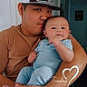 Benji is registered to the contest to win money with this photo: adult, baby, blue_clothing, cap, child, face, family, holding, indoor, love, person, portrait, smile, time_stamp, toddler, wall_art, arm, hand, foot, hat