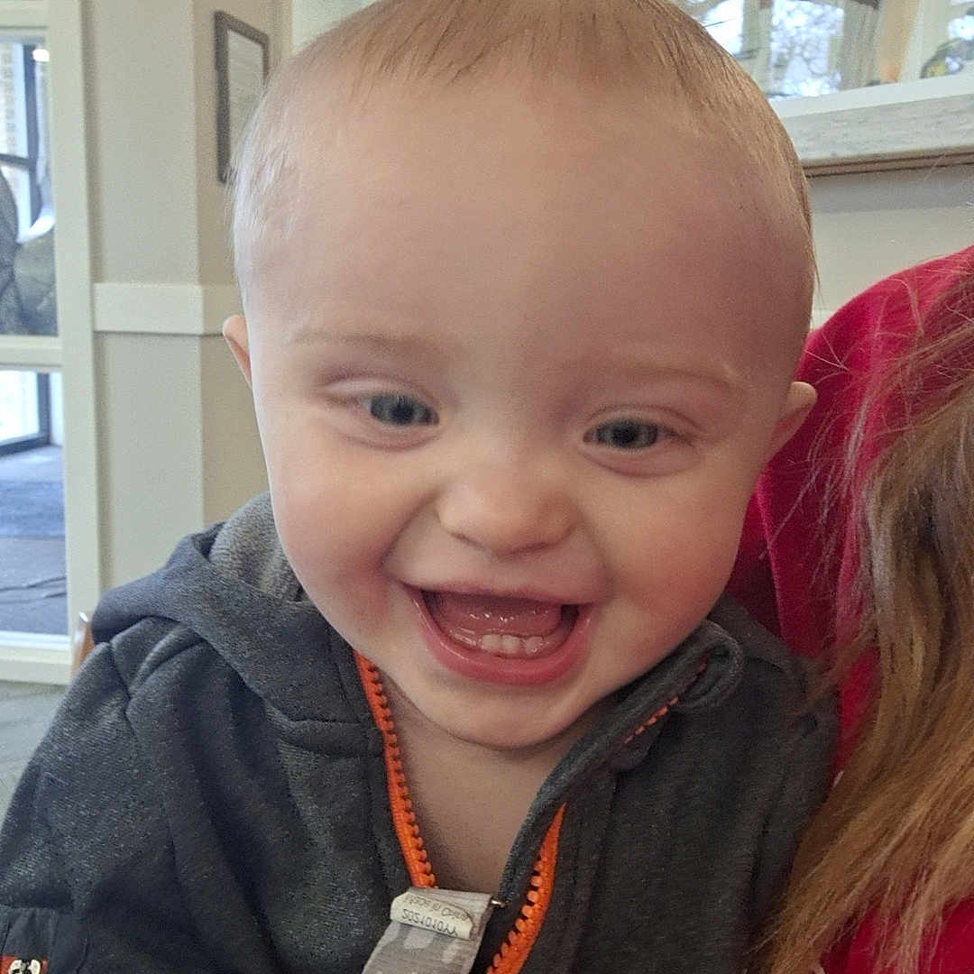 Bentley is registered to the contest to win money with this photo: baby, bodypart, clothing, coat, cutlery, face, fork, happy, head, jacket, knitwear, laughing, mouth, pants, person, photography, portrait, spoon, sweater, teeth