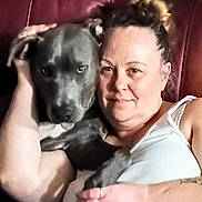 Jasper is registered to the contest to win money with this photo: woman, dog, pet, couch, chair, indoor, smile, casual, comfort, friendship, animal, human, relaxation, portrait, arm, hair, white_tank_top, tattoo, furniture, close_up