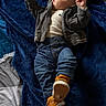 baby, infant, child, lying_down, blanket, navy_blue, denim, jacket, shirt, jeans, sneakers, orange_shoes, fashion, portrait, indoors, bed, face, looking_up, raised_arms, safe